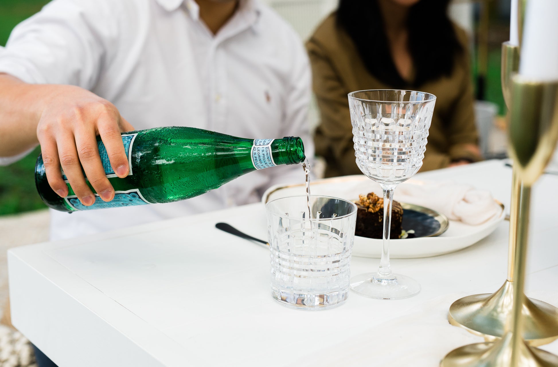 A person pouring water into a cut crystal old fashioned tumbler